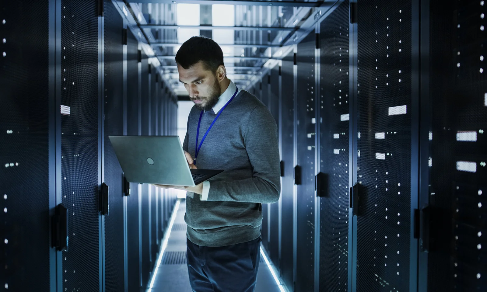 IT Professional Managing Data Servers in a High-Tech Server Room An IT professional working on a laptop in a high-tech server room, surrounded by rows of data servers.