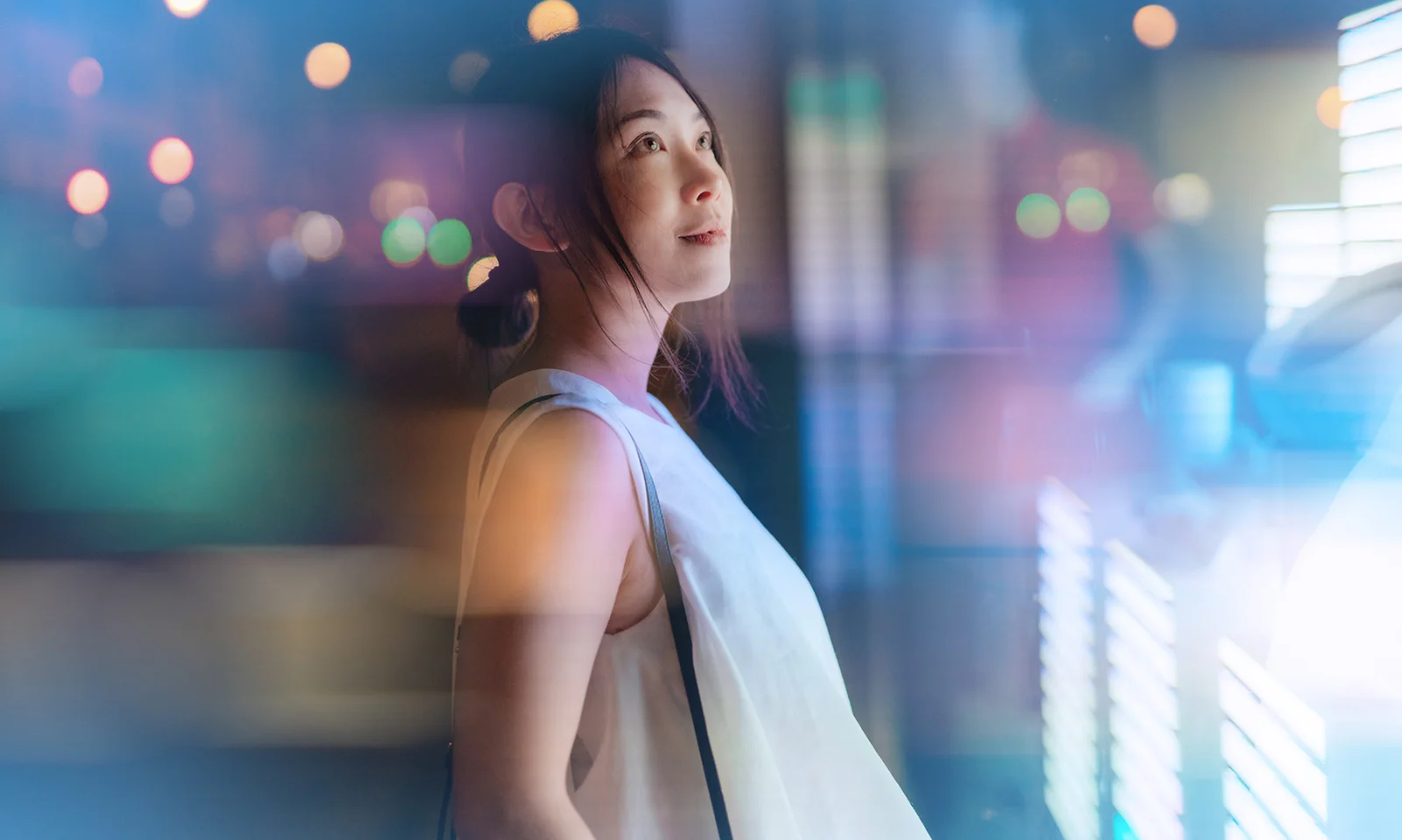 Recognition and Innovation: GFT's Commitment to Excellence A thoughtful woman looking up amidst vibrant city lights, symbolising inspiration and recognition in a modern digital landscape.