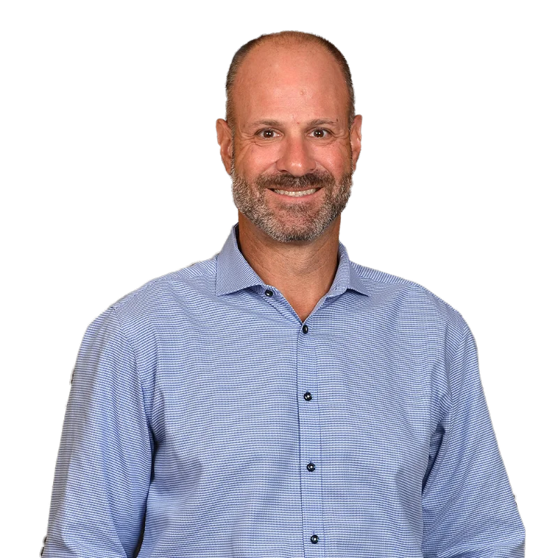 Portrait of Michael Pizzo wearing a light blue patterned shirt, smiling with a relaxed and approachable expression.