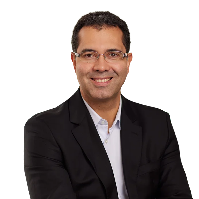 Marco Santos Portrait of Marco Santos in a black blazer and glasses.